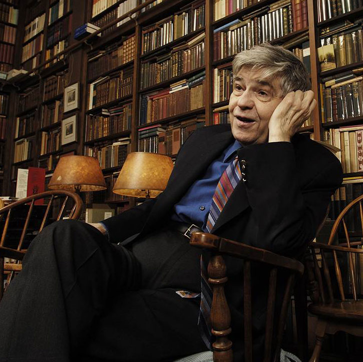 Photograph of Richard Macksey sitting in his library