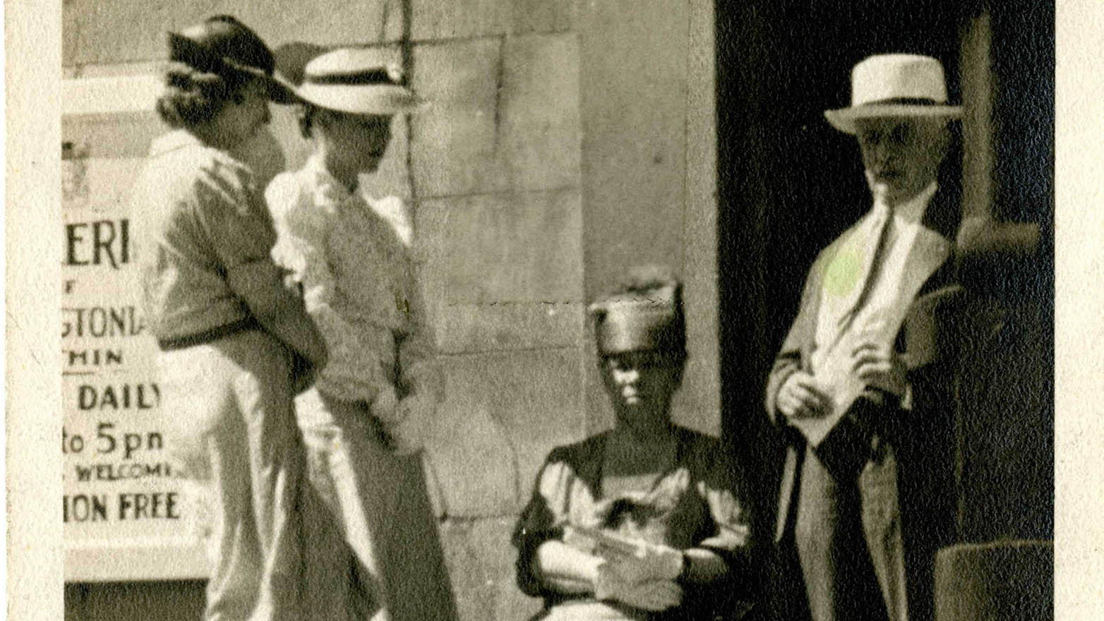 A black and white photograph shows Arthur Oncken Lovejoy standing outside of a building next to three women. Circa 1936.