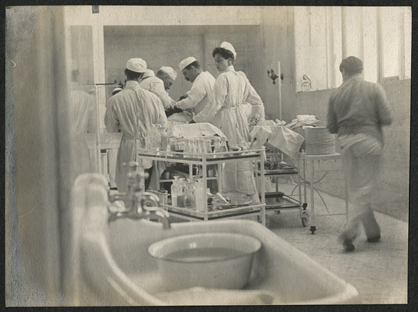 Caption: William Halsted with assistants and nurse performing surgery in operating room, circa 1903