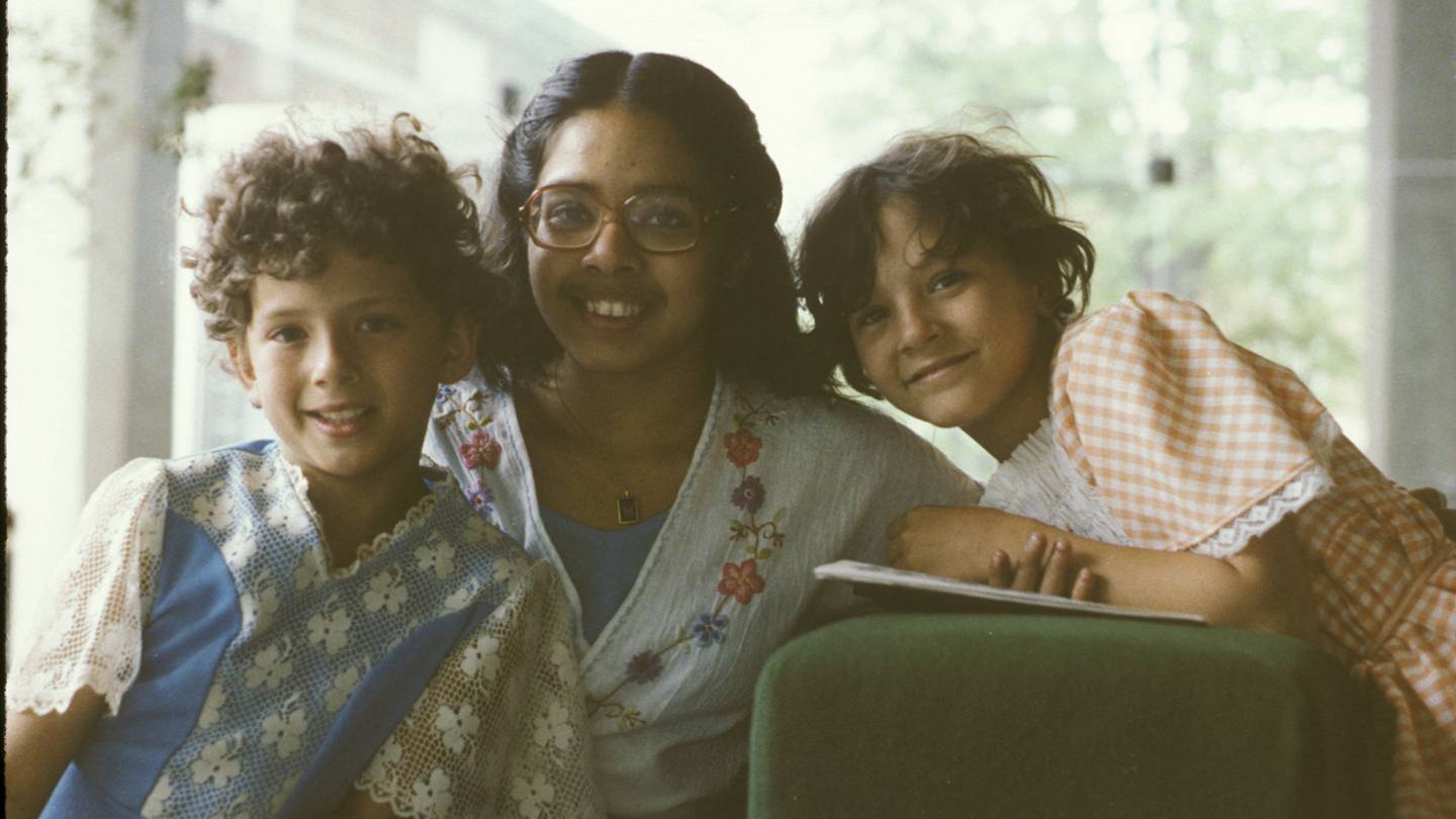 Three young girls smile in a dated photo