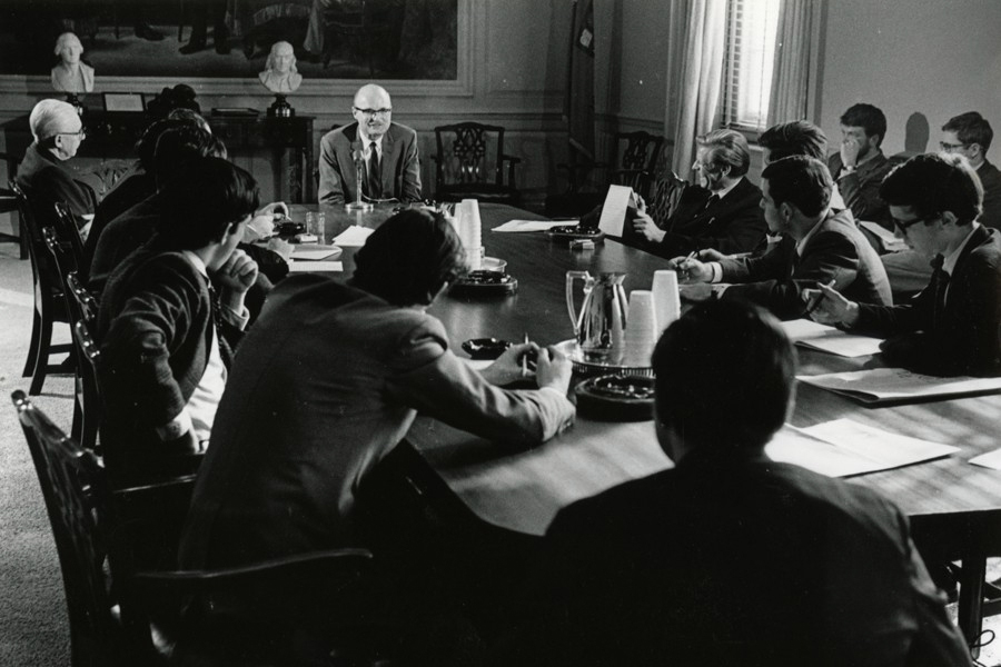 Black and white photo of students seated around a seminar table