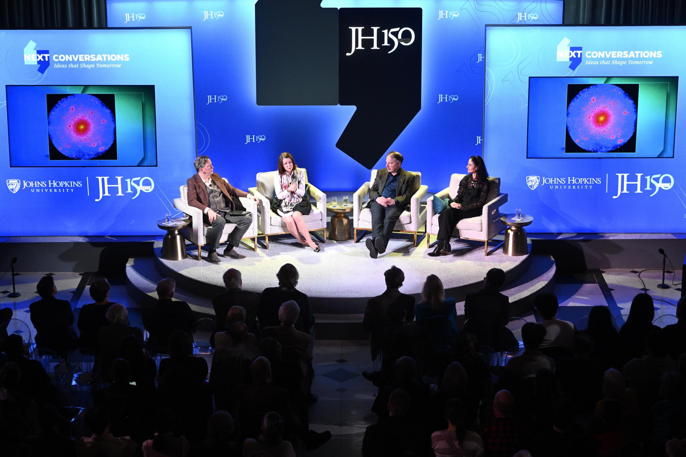 Four people sit on a stage for a discussion